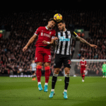 Pemain Liverpool dan Newcastle berebut bola di udara dalam pertandingan Liga Primer yang sengit.