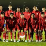 Pemain Timnas Indonesia U-17 berlatih sepak bola di lapangan hijau dengan latar belakang pegunungan dan stadion.