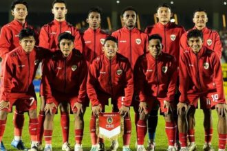 Pemain Timnas Indonesia U-17 berlatih sepak bola di lapangan hijau dengan latar belakang pegunungan dan stadion.